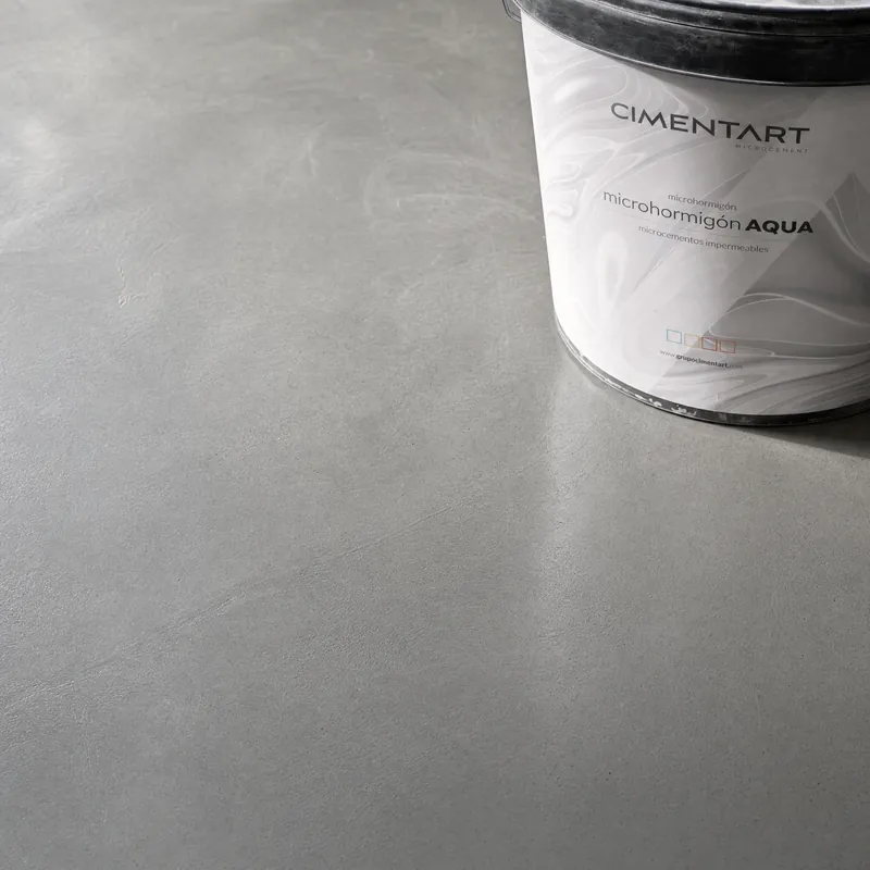 Close-up van een grijze vloer in microcement met een emmer